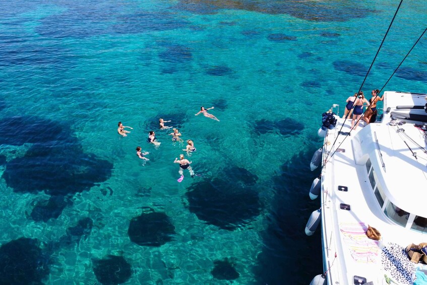 A group of people swimming in clear turquoise waters near a boat. 3