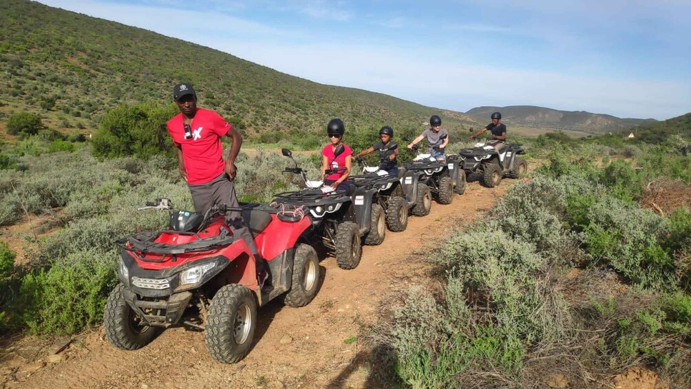 A group of people on ATVs in a dry, hilly landscape. 1