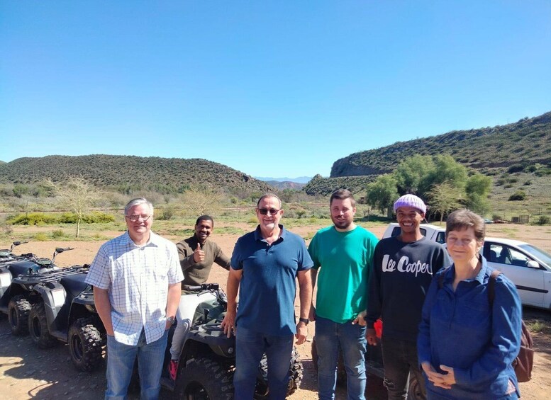A group of people standing in a desert landscape with mountains in the background. 2