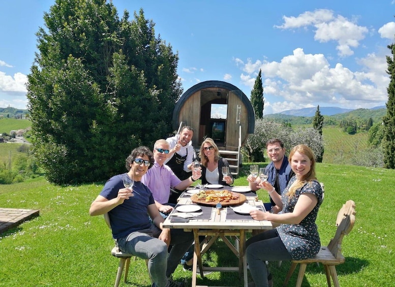 A group of people dining outdoors with a wooden barrel structure in the background. 3