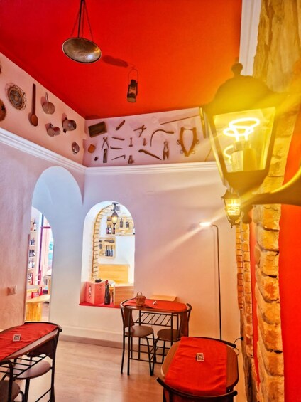 A restaurant interior with red walls, a stone wall, and a window with bottles. 5