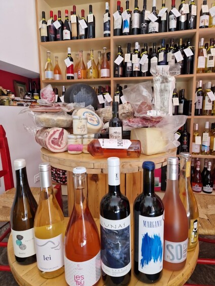 A variety of wine bottles and cheeses on display. 2