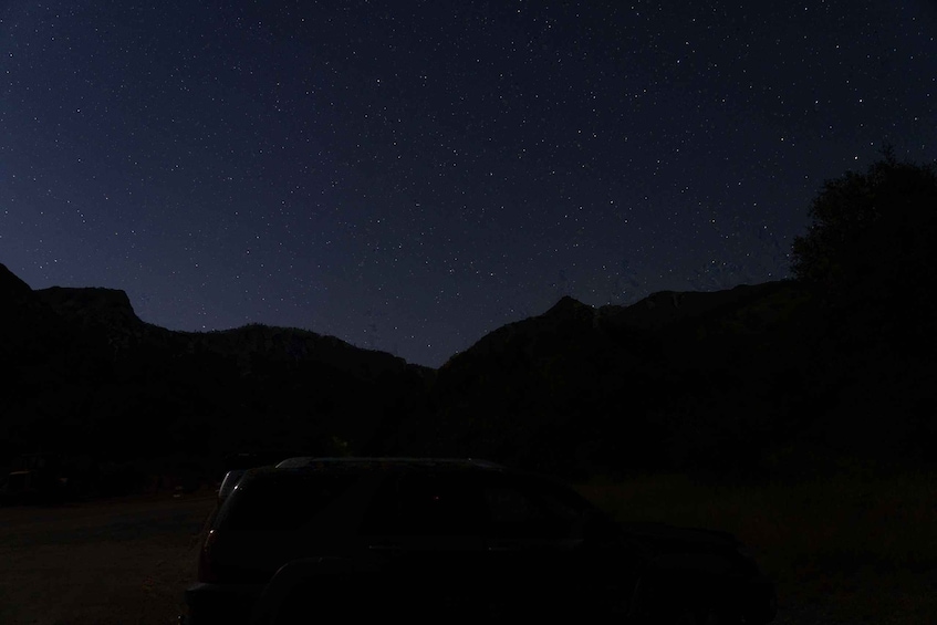 A car parked in a dark area with a starry night sky above. 5
