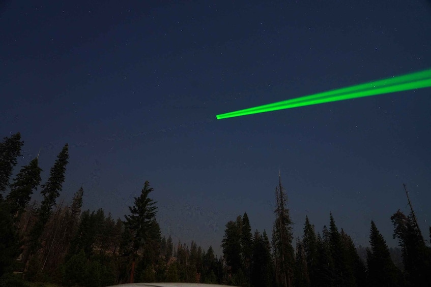 A night sky with a green laser beam and a forest. 4