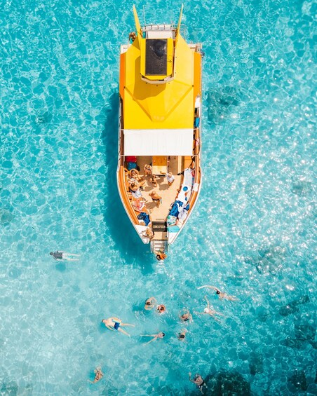 A yellow boat with passengers on a clear blue sea. 3