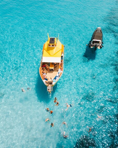 A yellow boat with people on board and swimmers in the water. 4