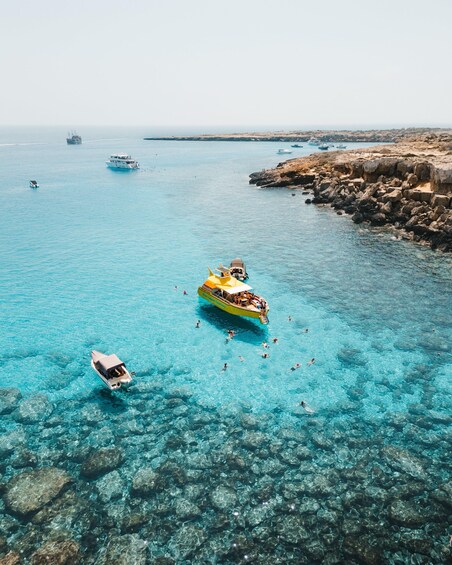 A clear blue sea with a yellow boat and a white boat. 5