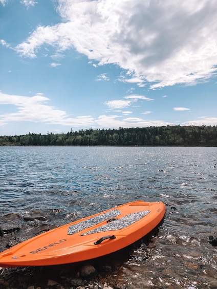 A clear lake with an orange kayak named 'SEAFLO' on the shore. 2