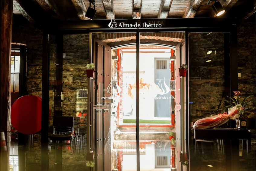 A restaurant entrance with a glass door, a red chair, and a potted plant. 2