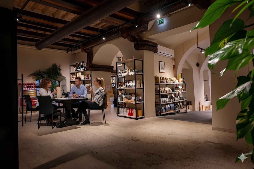 A group of people seated at a table in a warmly lit interior space with exposed wooden beams and arched ceilings. 1