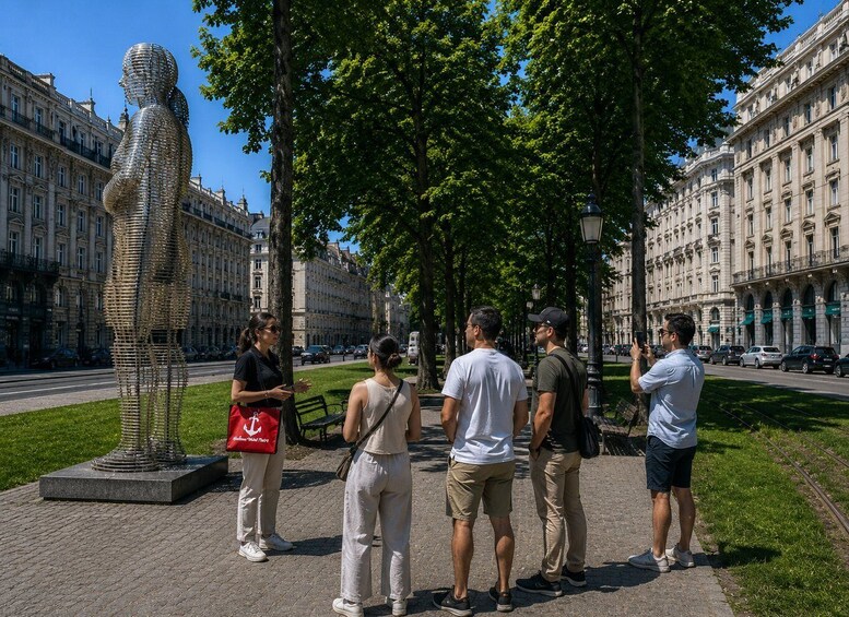A sculpture of a human figure made of metal, surrounded by trees and buildings. 2