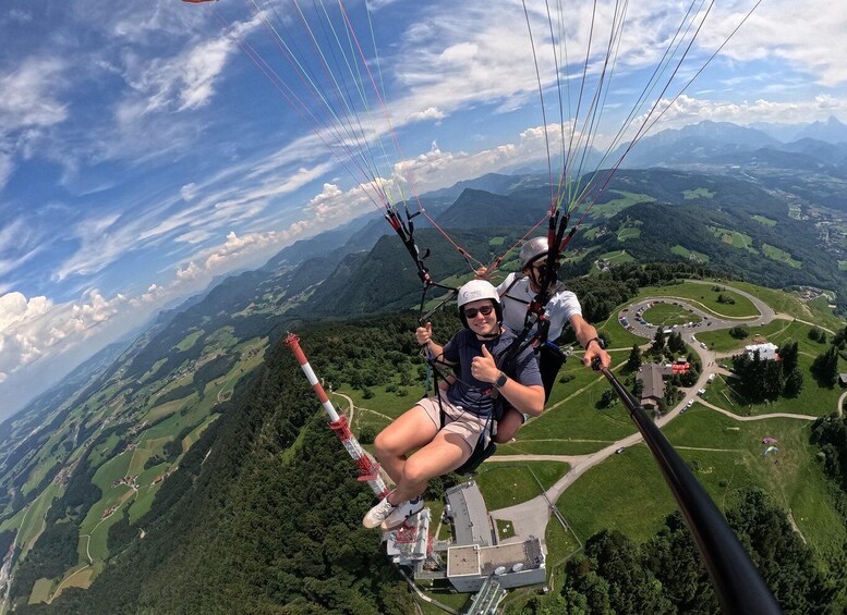 A person paragliding over a mountainous landscape with a clear sky. 1