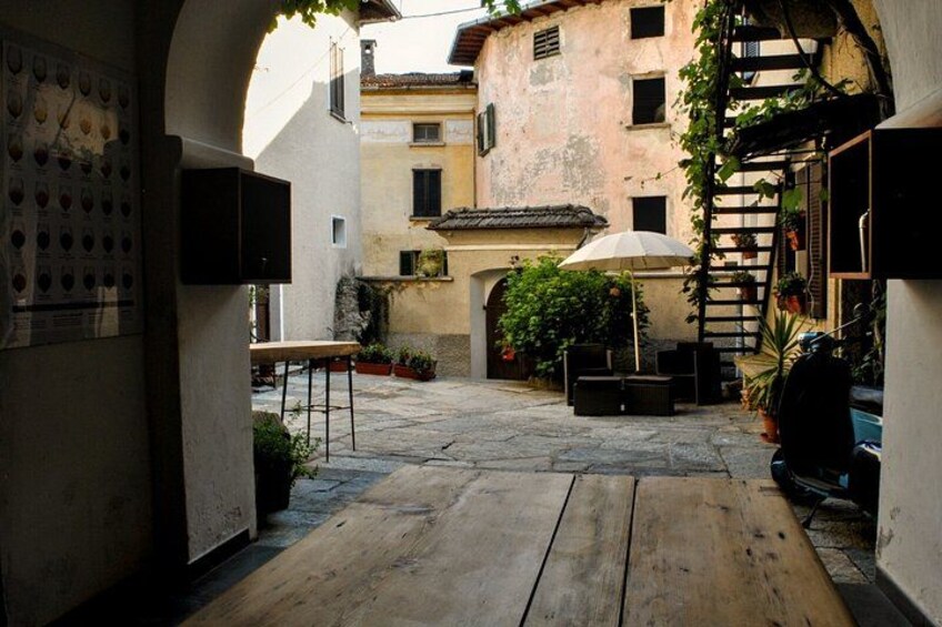 An outdoor courtyard with a wooden table, chairs, a ladder, and potted plants. 4
