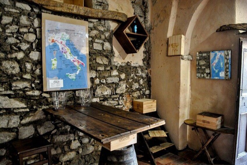 A rustic stone wall with a map of Italy, wooden furniture, and a small shelf with boxes. 5