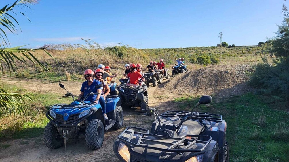 A group of people on ATVs on a dirt path in a rural area. 1