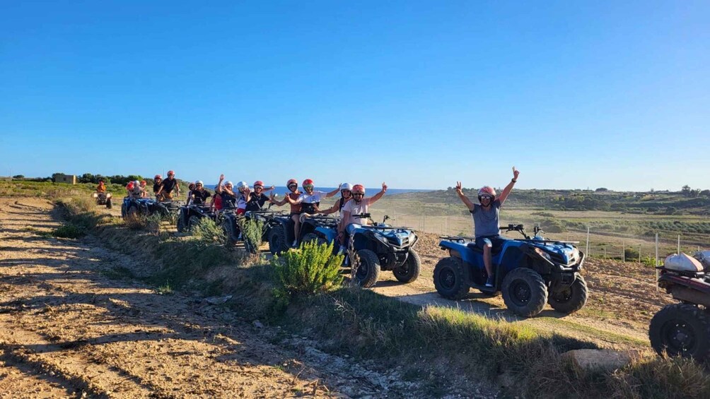 A group of people on ATVs on a dirt path with a clear sky and distant landscape. 2