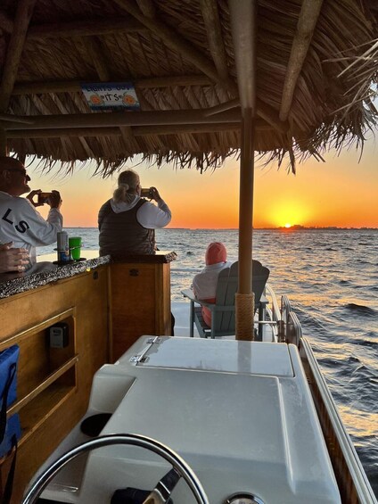 A boat with a thatched roof, a person taking a photo, and a sunset over the ocean. 1