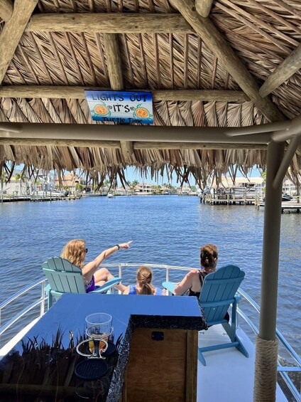 A boat with a thatched roof, people on board, and a sign reading 'Lights Out It's Turtle Time'. 3