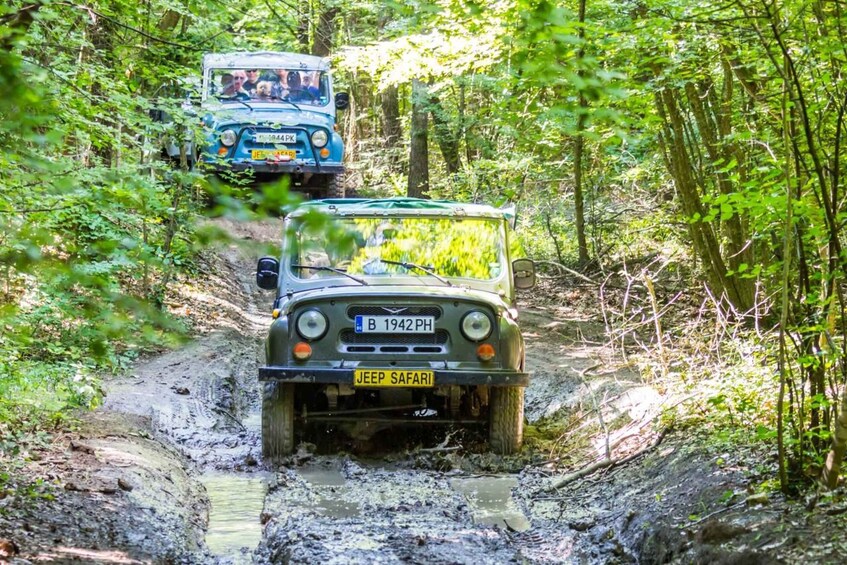 Two off-road vehicles navigating a muddy forest trail. 2