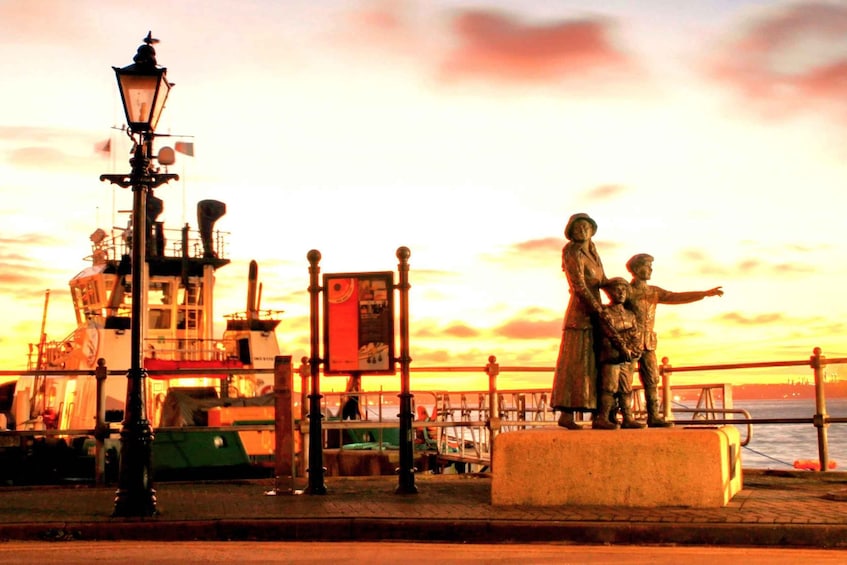 A statue of a man and a child on a waterfront at sunset. 2
