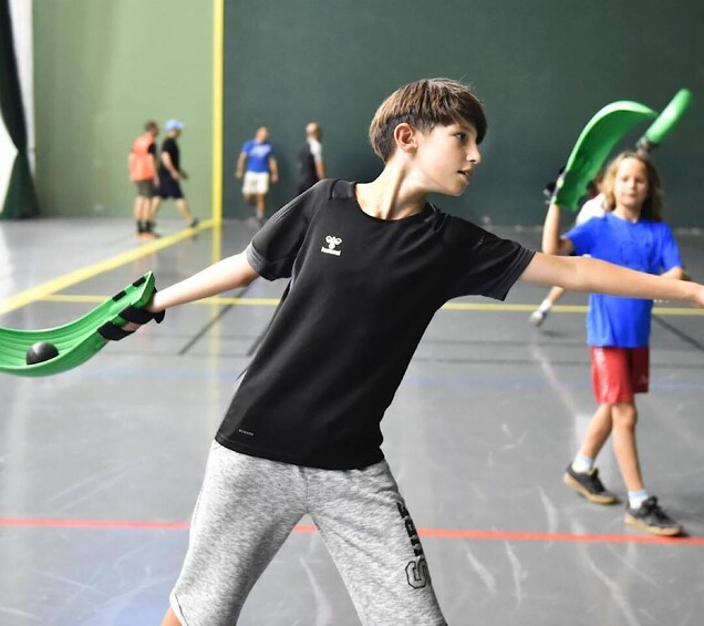 A person playing tennis indoors with a racket and ball. 4
