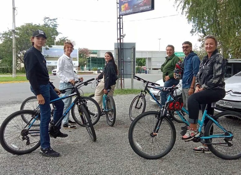 A group of people standing and sitting with bicycles in an outdoor setting. 3