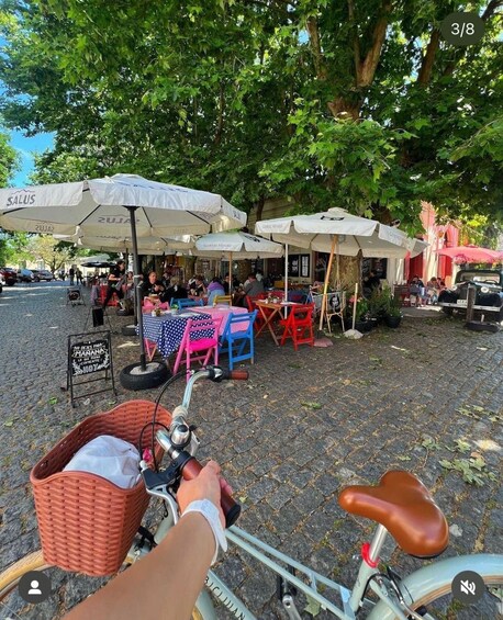 A bicycle with a basket and a seat, parked on a cobblestone path. 2
