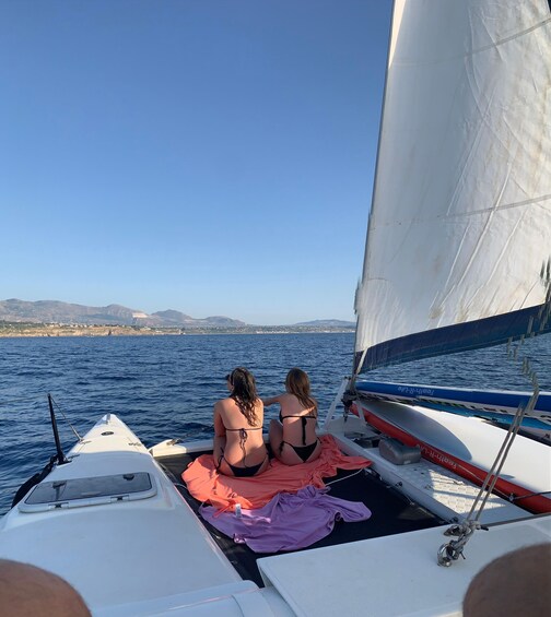 Two people on a sailboat with a view of the sea and distant land. 2