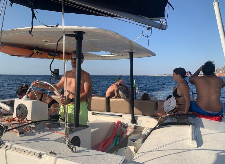 A sailboat with people on board, a clear sky, and calm sea. 3