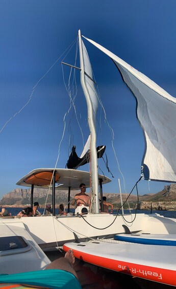 A sailboat with a person steering, surrounded by calm waters and rocky cliffs. 4