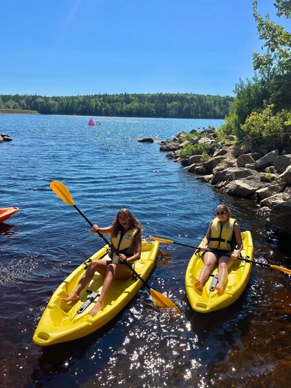 Two people kayaking on a calm lake surrounded by rocks and trees. 1