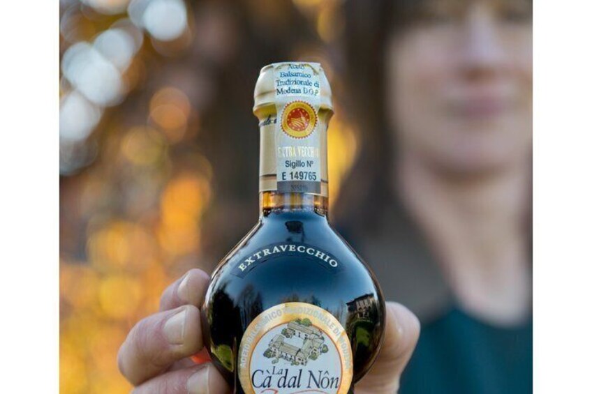 A person holding a bottle of Cà dal Nò with a label that includes the text 'EXTRAVECCHIO' and 'Sigillo N° 149765'. 3