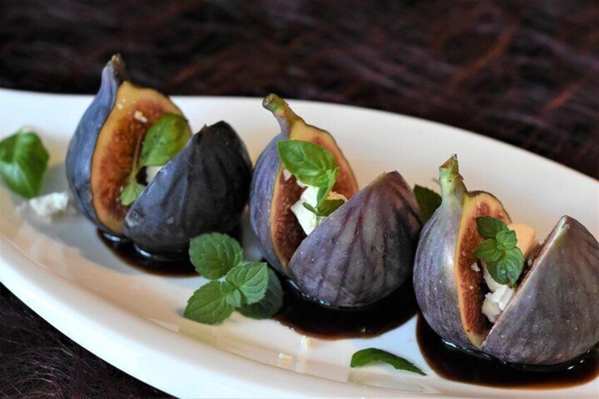 Figs with a dark purple skin, some cut open, and garnished with mint leaves. 2