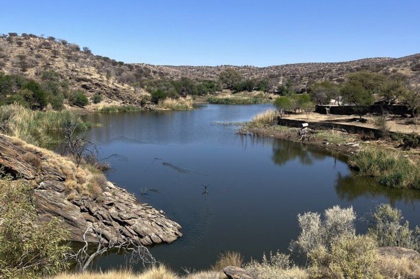 A calm river with rocky banks, sparse vegetation, and a clear sky. 3