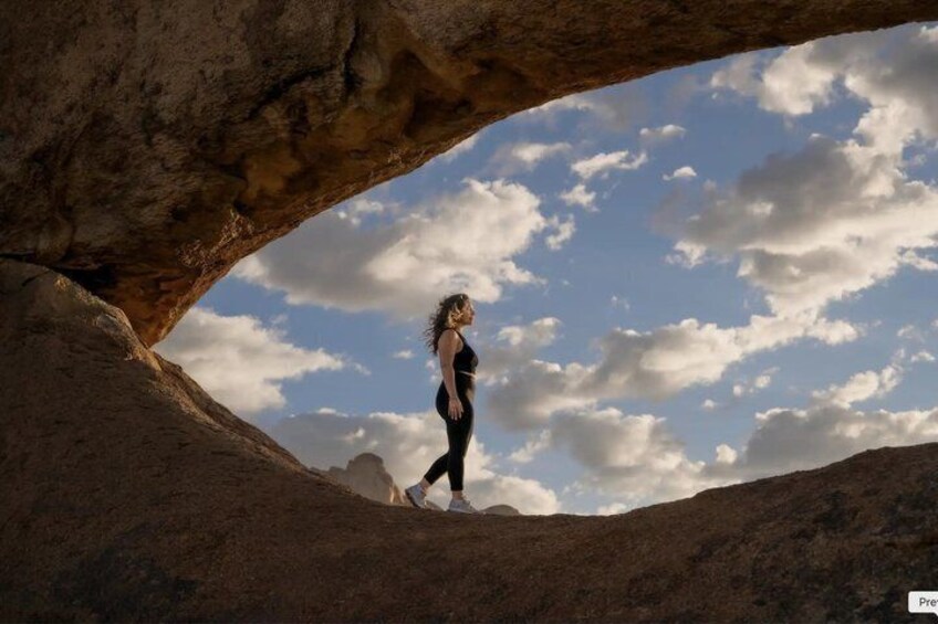 A person walking through a natural rock arch formation. 1