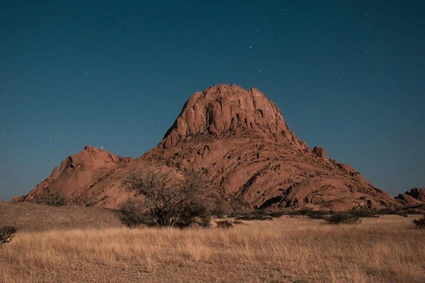 A large reddish-brown mountain under a clear night sky. 2