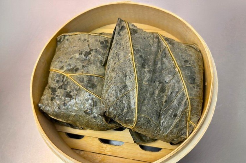A bamboo steamer containing several wrapped items tied with string. 2