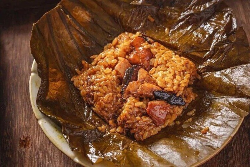 A dish of rice and meat wrapped in banana leaves on a plate. 1