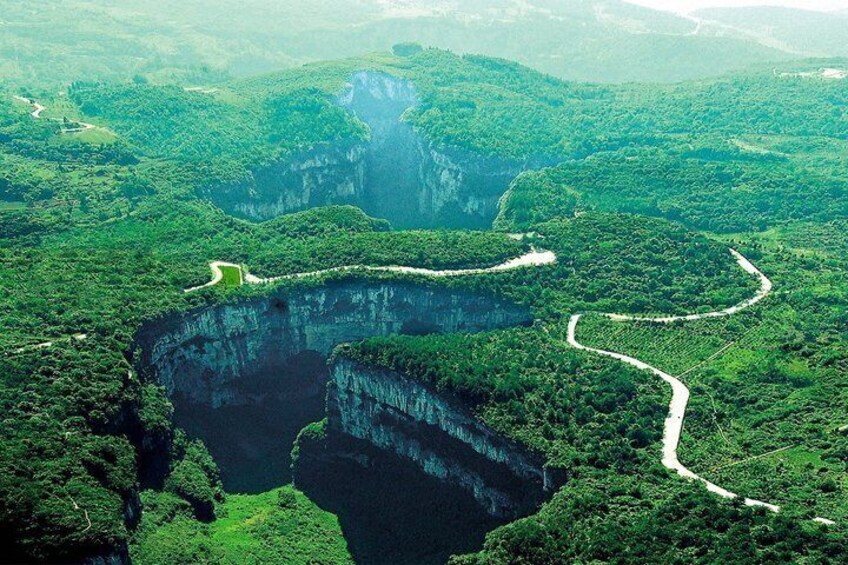 A deep gorge with winding paths and lush greenery. 1
