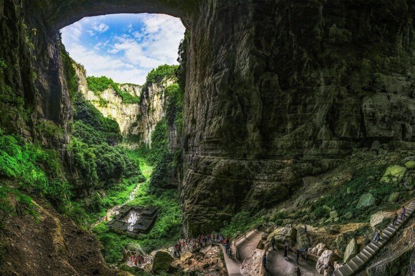 A canyon with a narrow passageway, lush greenery, and a stone structure at the bottom. 5