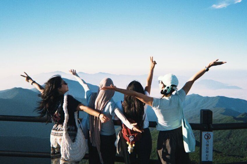 A group of people standing with arms outstretched, overlooking a mountainous landscape. 1