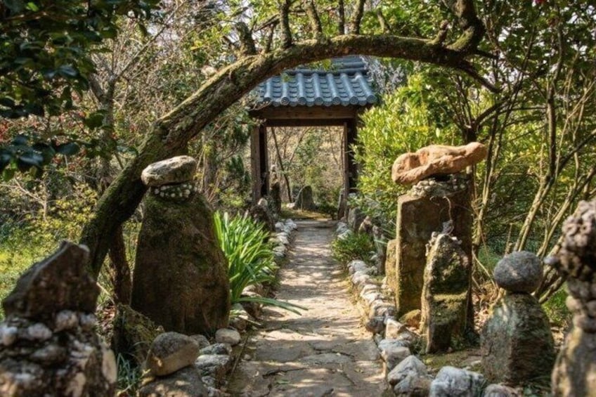 A stone pathway leading to a traditional Japanese-style pavilion surrounded by rocks and foliage. 5