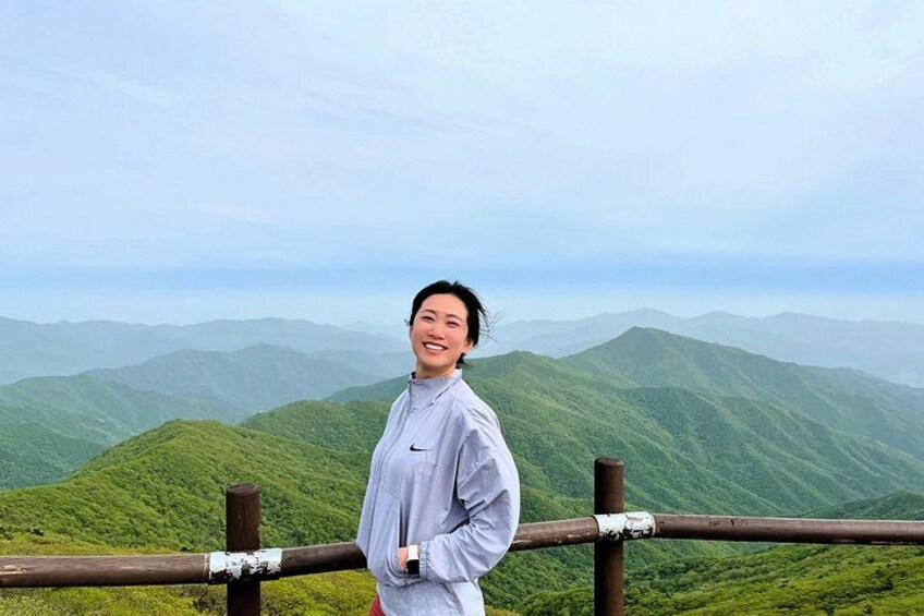 A person standing on a wooden railing overlooking a mountainous landscape. 3