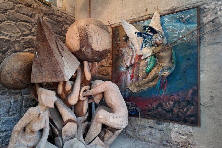 A sculpture of intertwined wooden elements and a painting of a figure with wings. 4