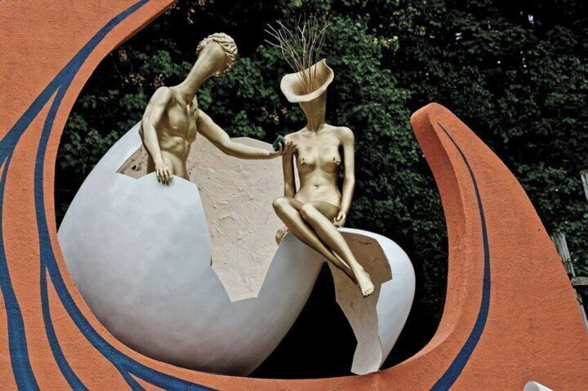 A sculpture of two figures on a large egg-shaped structure with a curved design. 3