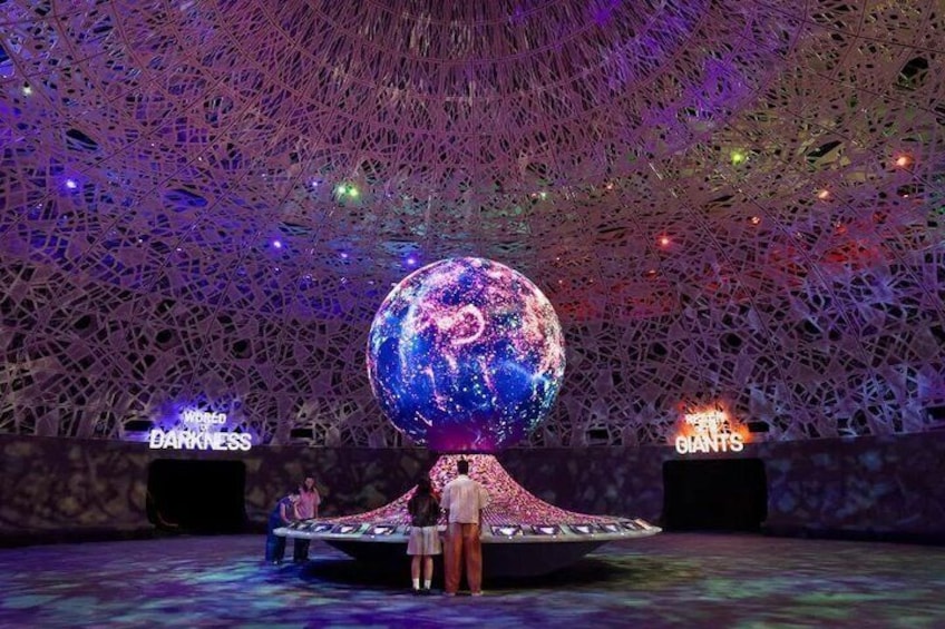 A large spherical structure with a space-themed design, surrounded by a complex geometric ceiling. 1
