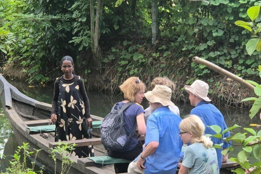 A group of people on a wooden boat in a forested area with dense greenery and a calm river. 2