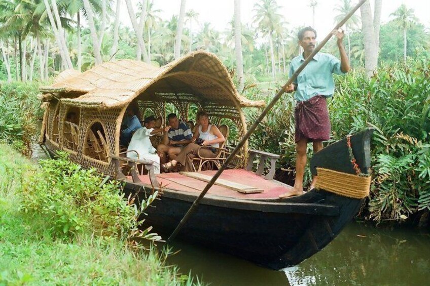 A traditional boat with passengers, surrounded by lush greenery and palm trees. 1