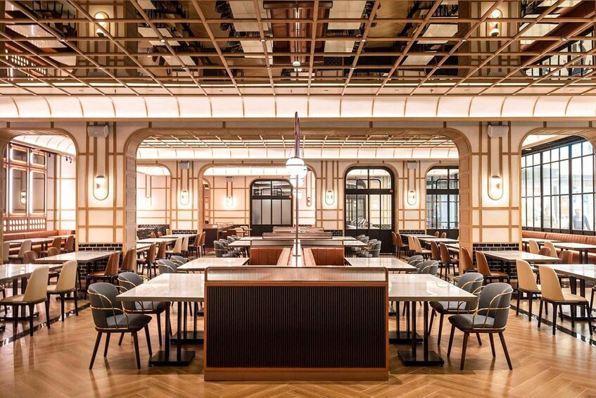 A spacious restaurant with high ceilings, large windows, and a central island. 1