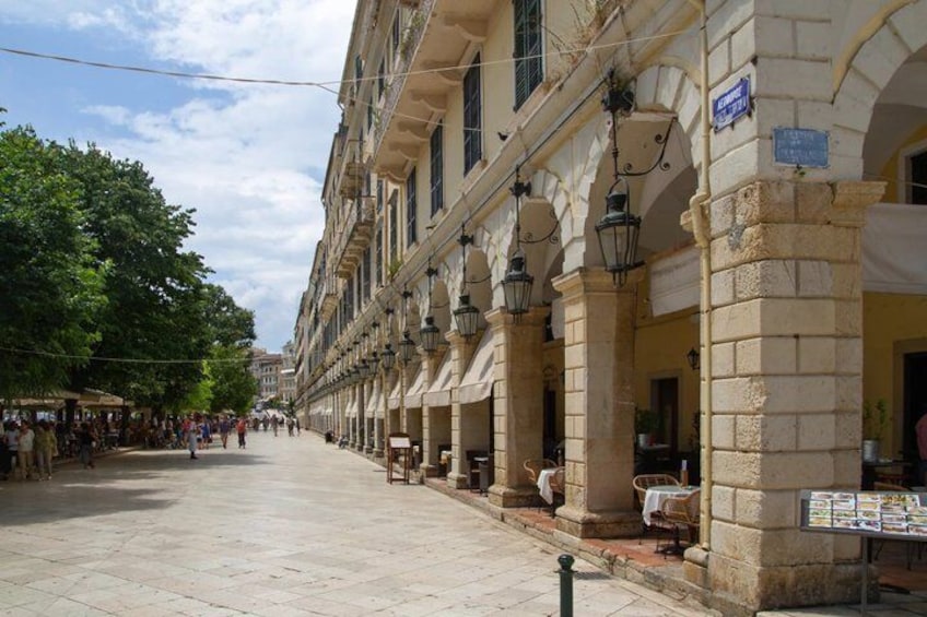 A pedestrian street lined with historic buildings, outdoor cafes, and a clear sky. 4